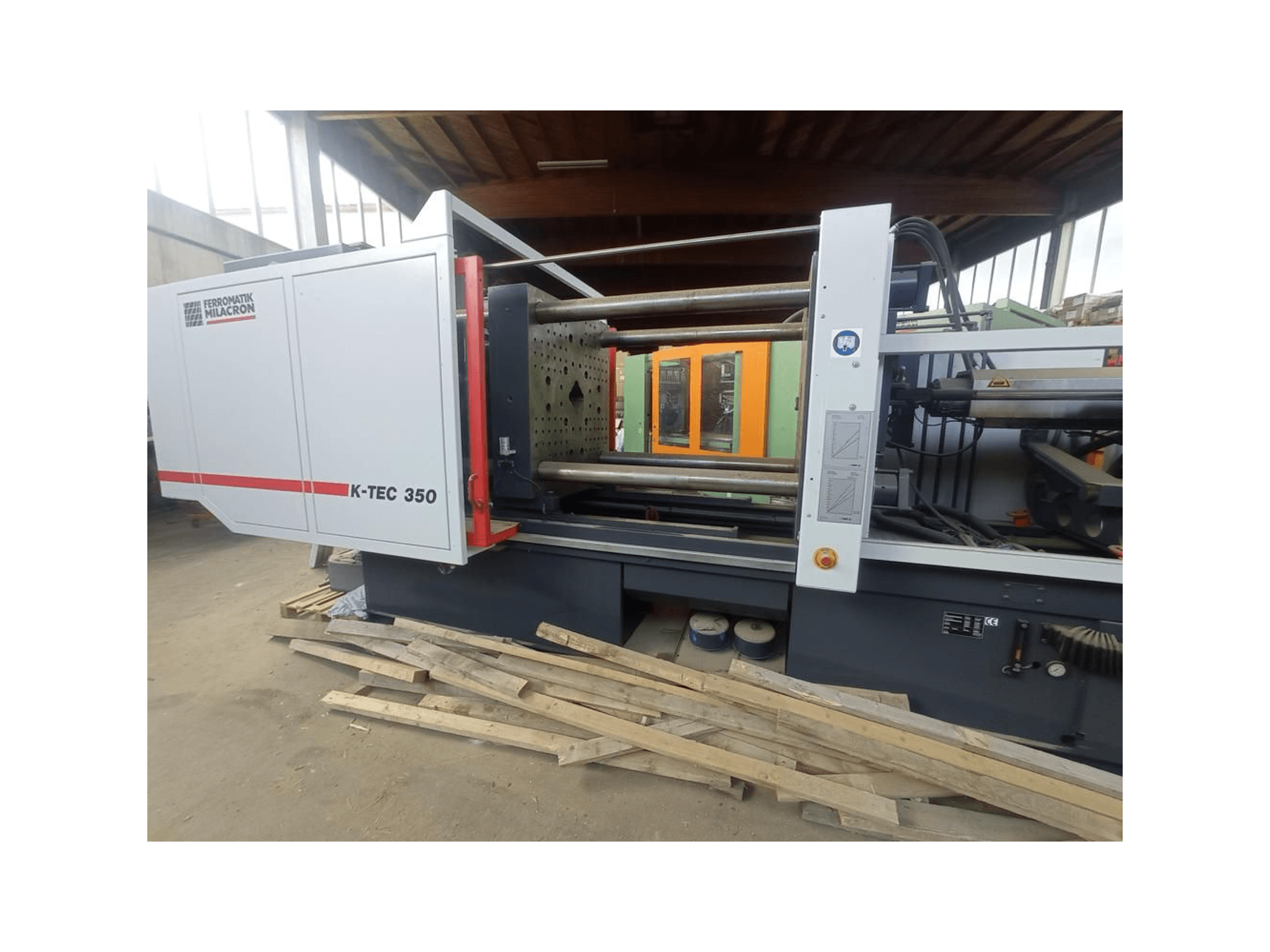 A Ferromatik Milacron K-TEC 350, oldalnézetből, amely a komplex gépezetet és a működési vezérlést mutatja be.